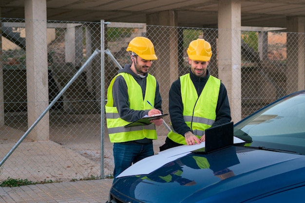 Twee mannen met een helm en een reflecterend hesje werken in de bouw