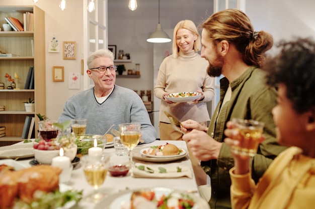 Twee mannen praten met elkaar terwijl volwassen vrouw eten op tafel draagt