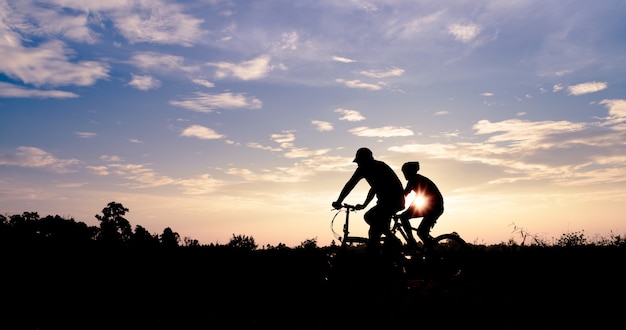 Twee mannen rijdt fietsen op de weg bij zonsondergang hemelachtergrond.