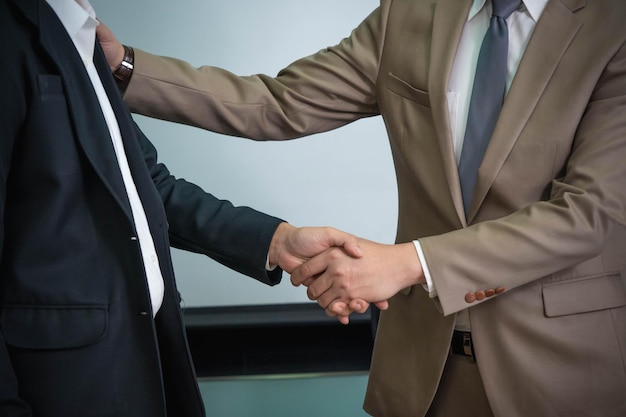 Twee mannen schudden elkaar de hand, een van hen draagt een pak.