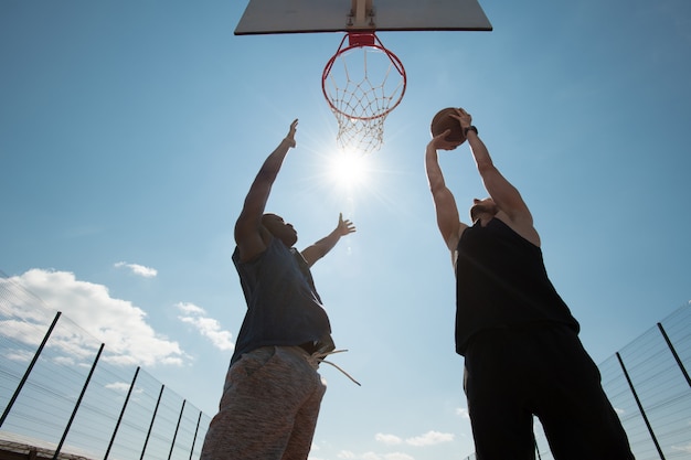 Twee mannen spelen basketbal buitenshuis