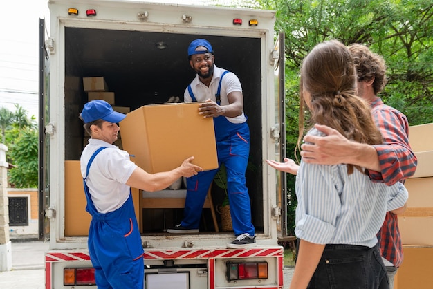 Twee mannen verhuizers in blauw uniform tillen kartonnen doos op uit vrachtwagen voor verhuisservice