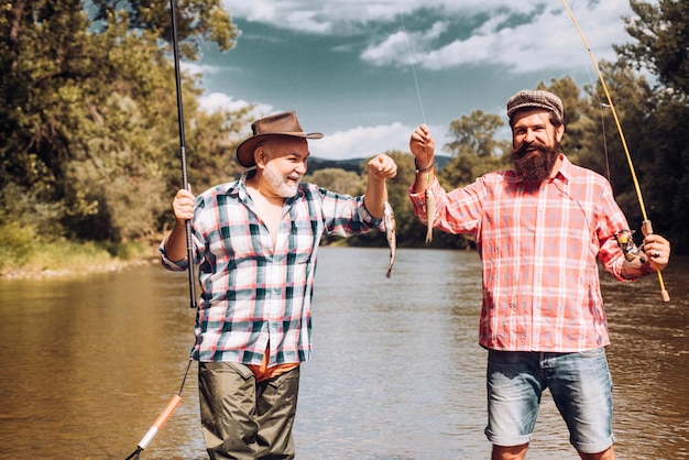 Twee mannen vrienden visser vissen op de rivier Oude vader en zoon met hengel vissen aan de rivier Recreatieve activiteit Forel vissen