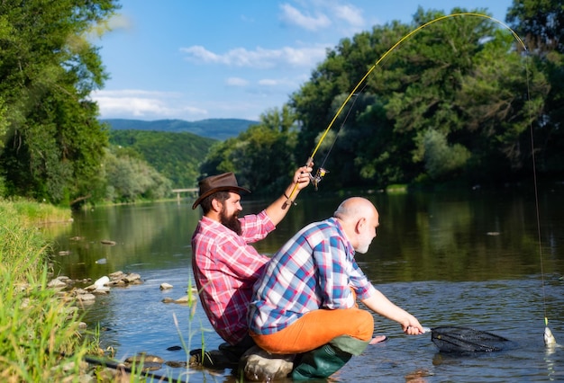 Twee mannen vrienden visser vissen op rivier oude vader en zoon met hengel vissen aan de rivier recreati