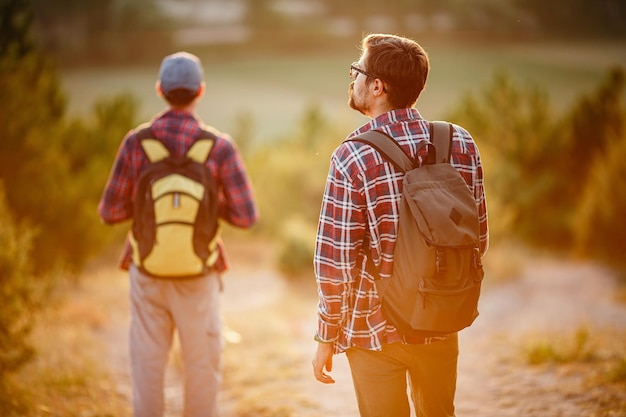 Twee mannen wandelaars genieten van een wandeling in de natuur bij zonsondergang in de zomer