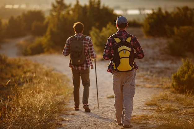 Twee mannen wandelaars genieten van een wandeling in de natuur bij zonsondergang in de zomer