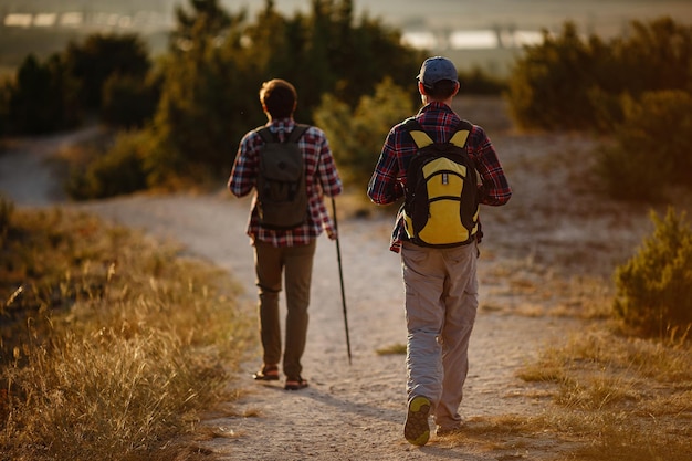 Twee mannen wandelaars genieten van een wandeling in de natuur bij zonsondergang in de zomer