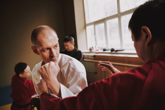 Twee mannen werken de kungfu-techniek van impact uit in de sportschool.