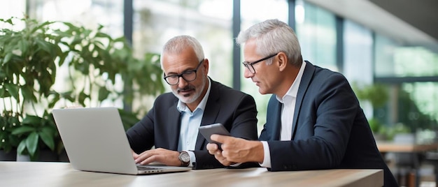 twee mannen zitten aan een bureau met laptops en een creditcard op de achtergrond