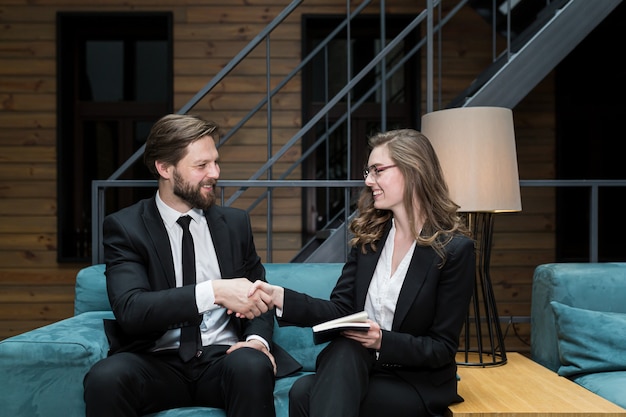 Twee medewerkers die elkaar de hand schudden in een vergadering