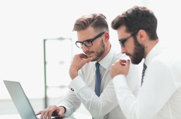 Twee medewerkers gebruiken een laptop terwijl ze aan hun bureau zittenhet concept van professionaliteit