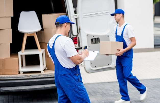 Twee medewerkers van het verhuisbedrijf laden dozen in een minibus