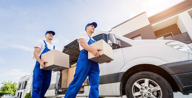 Twee medewerkers van het verhuisbedrijf lossen dozen uit minibus naar huis van klanten