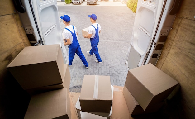 Twee medewerkers van het verhuisbedrijf lossen dozen uit minibus