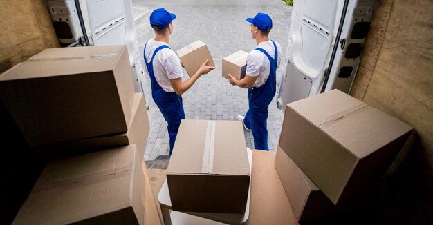 Twee medewerkers van het verhuisbedrijf lossen dozen uit minibus