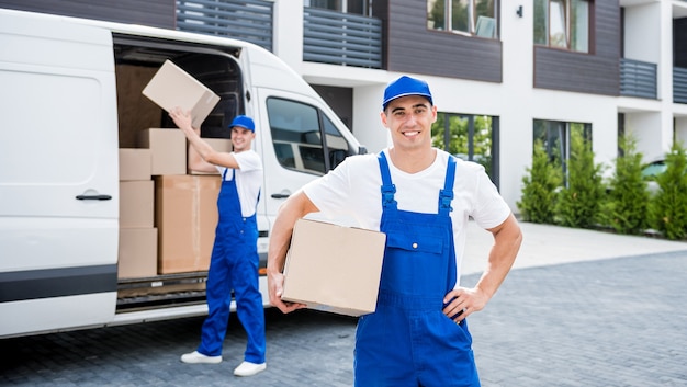 Twee medewerkers van het verhuisbedrijf lossen dozen van minibus in nieuwe woning