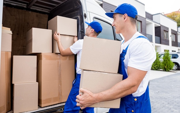 Twee medewerkers van het verhuisbedrijf lossen dozen van minibus in nieuwe woning