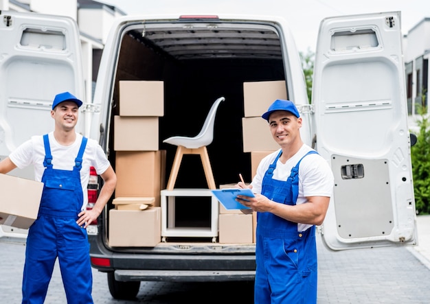 Twee medewerkers van het verhuisbedrijf lossen dozen van minibus naar huis van klanten