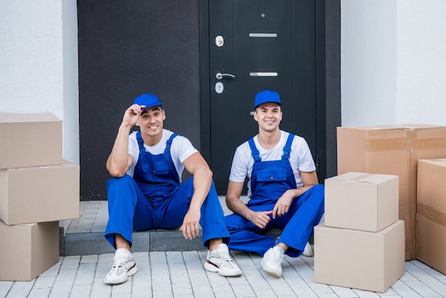 Twee medewerkers van het verhuisbedrijf pauzeren zittend op het opstapje