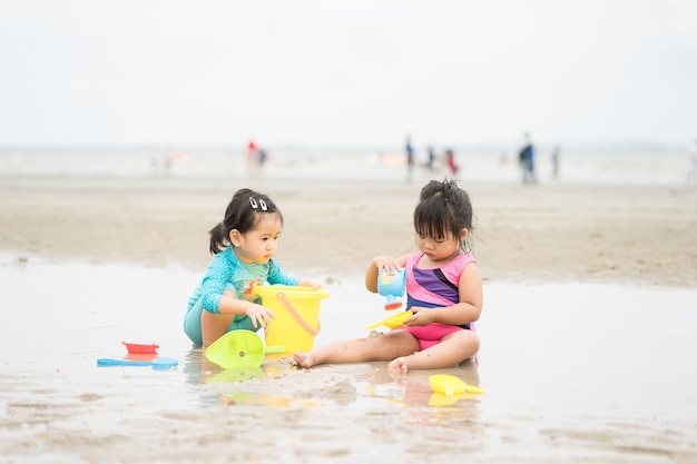 twee meisje zand spelen op het strand