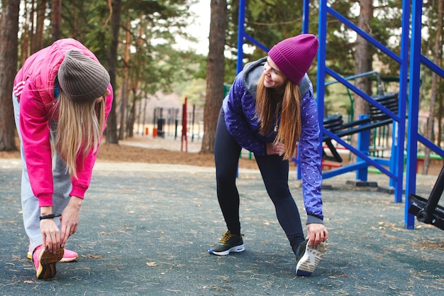 Twee meisjes atleten in de sport doen fysieke oefeningen op de buitenspeeltuin in het bos. Een gezonde leefstijl