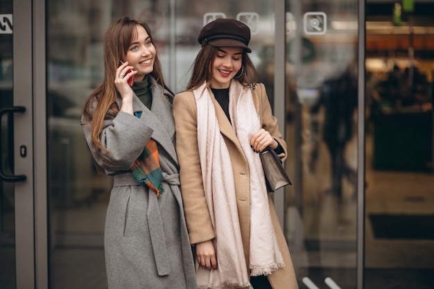 Twee meisjes buiten winkelcentrum met telefoon in een de herfstdag