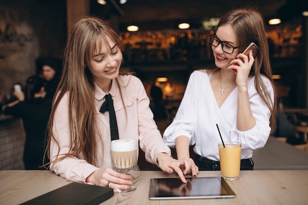 Twee meisjes die aan een tablet in een koffie werken