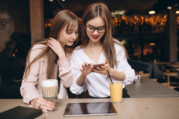 Twee meisjes die aan een tablet in een koffie werken