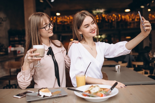 Twee meisjes die lunch in een koffie hebben en selfie doen