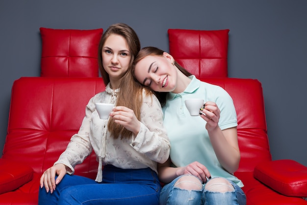 Twee meisjes die met kopjes koffie samen zitten