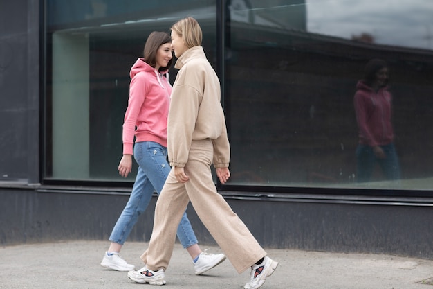 Twee meisjes die op de stadsstraat lopen. Jonge vrouw buitenshuis.