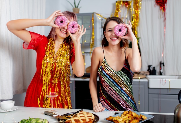 Twee meisjes die plezier hebben met donuts in de keuken na een feestje