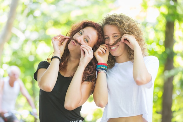 Twee meisjes die snor met hun haar maken.