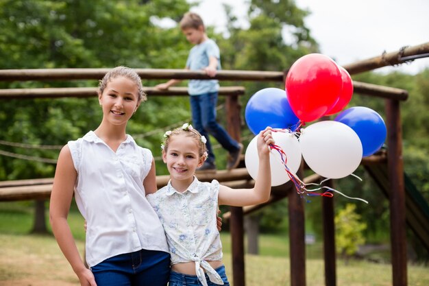 Twee meisjes die terwijl het houden van ballons in park glimlachen