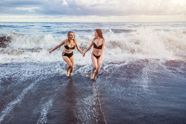 Twee meisjes die van de golven rennen