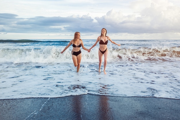 Twee meisjes die van de golven rennen