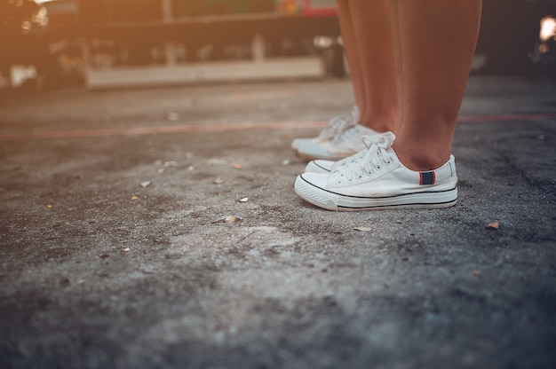 Twee meisjes die zich naast elkaar bevinden die witte schoenen dragen.