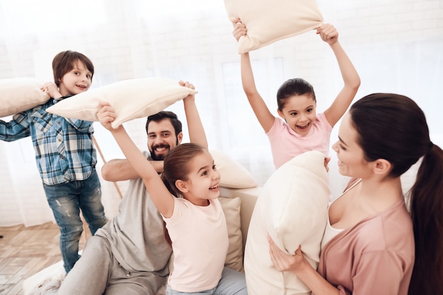 Twee meisjes en een jongen vechten met kussens met hun ouders.