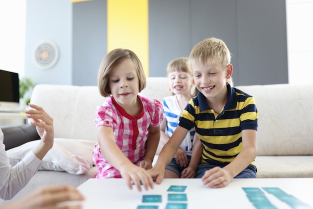 Twee meisjes en een jongen zitten op de bank en spelen bordspel