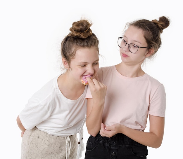 Twee meisjes eten zoete donut en glimlachen Studio portret op witte achtergrond