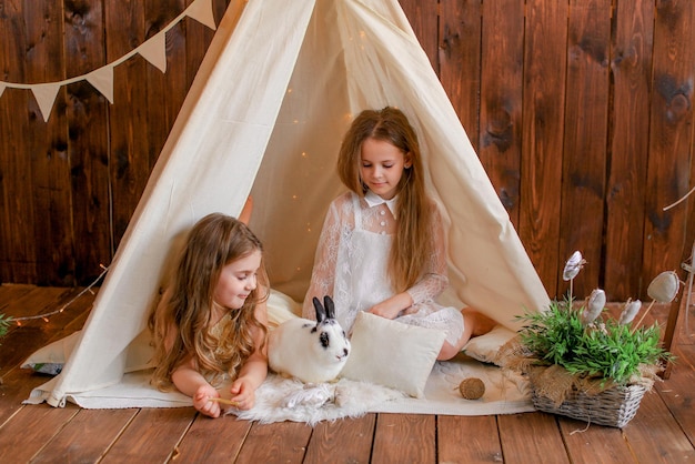 twee meisjes in een tent wigwam met een konijn, paasthema