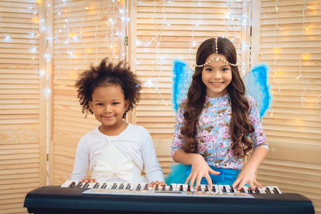 Twee meisjes in feestelijke attires spelen piano