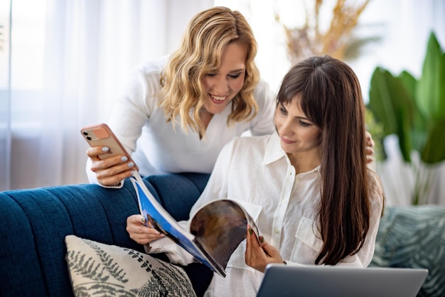 Twee meisjes in overhemden bespreken iets terwijl ze naar de telefoon en een tijdschrift in het appartement kijken