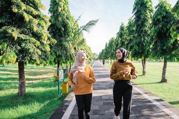 Twee meisjes in sluier doen buitensporten terwijl ze samen joggen in de tuin