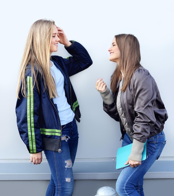 twee meisjes lopen lachend door de straten en maken foto's met een smartphone