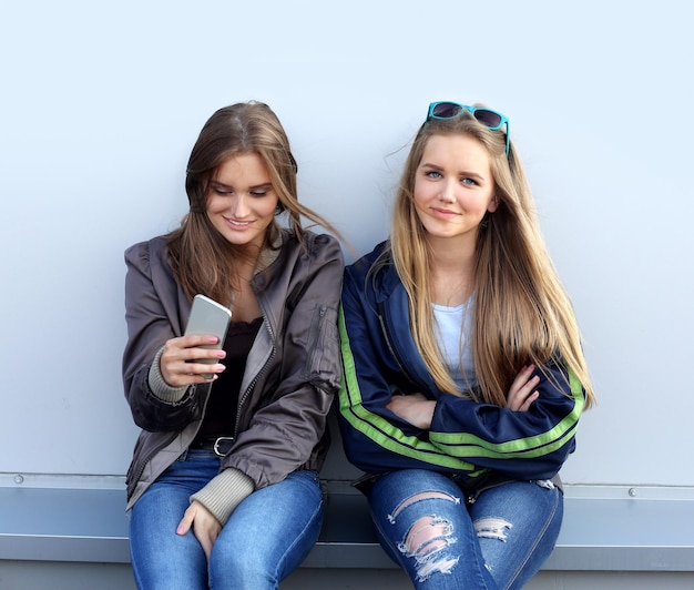 twee meisjes lopen lachend door de straten en maken foto's met een smartphone