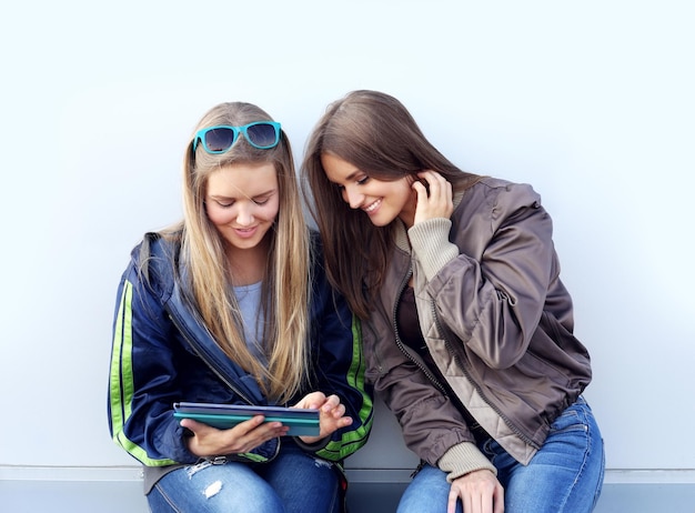 twee meisjes lopen lachend door de straten en maken foto's met een smartphone