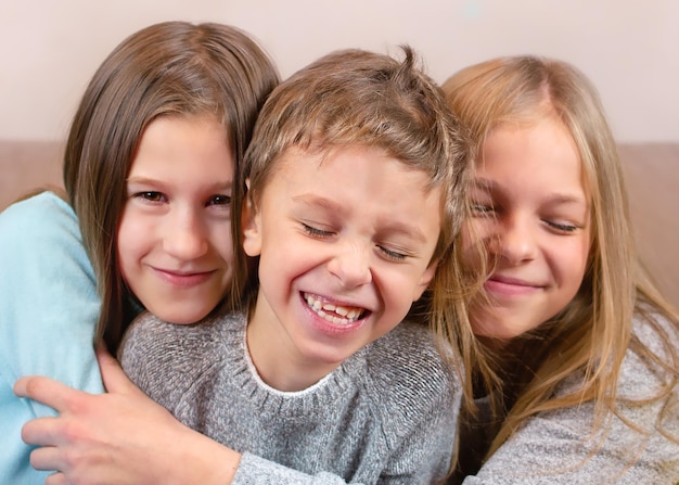 Twee meisjes omhelzen hun broer. De jongen lacht. Gelukkige kinderen portret close-up