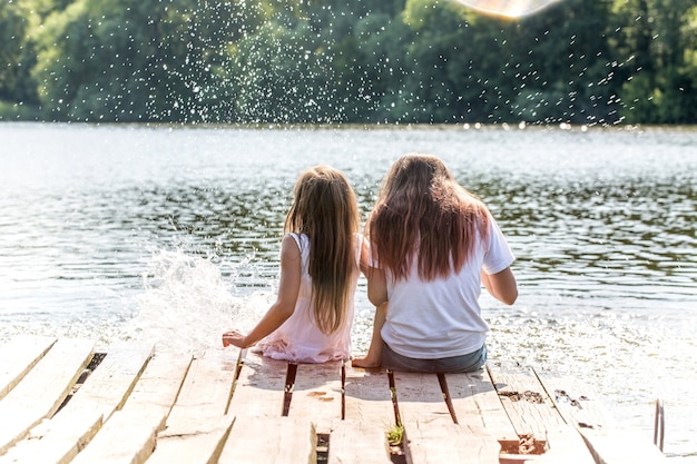 Twee meisjes ontspannen bij de rivier in de zonnestralen. Foto's met hoogtepunten