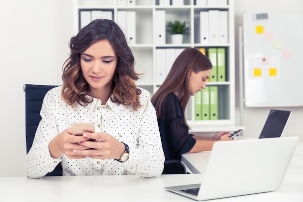 Twee meisjes op kantoor controleren hun telefoons